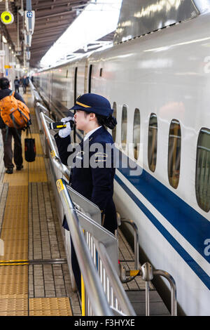 La gare de Nagoya, femme d'orchestre sur la plate-forme clearing Shinkansen, le train à grande vitesse, à partir du métro, ce qui annonce pour les gens de se tenir à l'écart. Banque D'Images