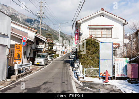 Le Japon, ville rurale Ville de montagne de Nagiso, vue le long de ruelles rue ville japonaise après un peu de neige. Panneau d'avertissement jaune, l'homme au travail. Banque D'Images