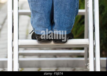 Pieds de femme en noir chaussures le jardin en échelle en aluminium Banque D'Images