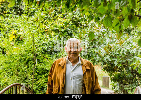 Veste en daim avec senior et chemise blanche dans un parc verdoyant, smiling Banque D'Images