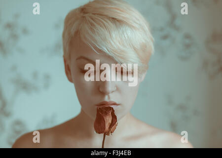 Blonde teenage girl holding a dead rose Banque D'Images