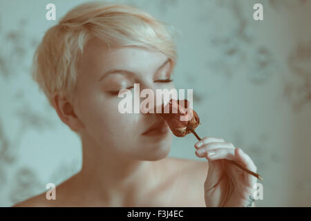 Blonde teenage girl holding a dead rose Banque D'Images