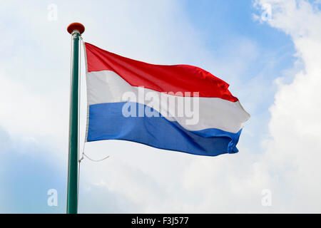 Brandir le drapeau néerlandais dans l'air sur un jour nuageux Banque D'Images