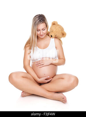 Portrait of a happy pregnant woman sitting on floor and holding belly Banque D'Images