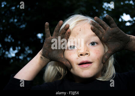 Portrait de petit enfant fille blonde montrant les mains pleines de terre