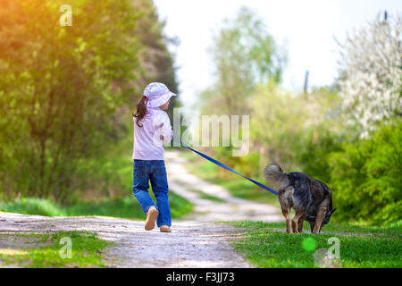 Happy little girl avec chien qui court dans la campagne Banque D'Images