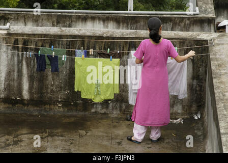 Woman hanging chiffons lavés sur chaîne pour le séchage sur terrasse ouverte à Pune Maharashtra Inde Asie Banque D'Images