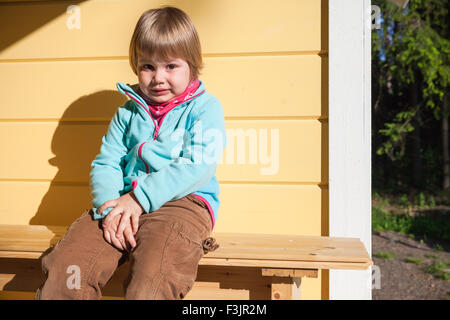 Portrait de plein air confus Caucasian blonde près de mur de la maison en bois en milieu rural