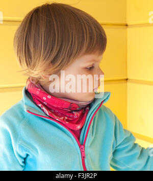 Closeup portrait of cute profil Caucasian blonde au mur en bois jaune Banque D'Images