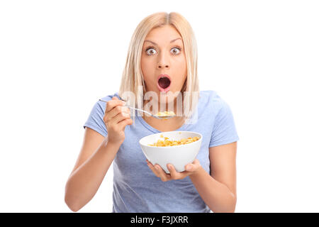 Choqué woman eating cereal à partir d'un bol et regardant la caméra isolé sur fond blanc Banque D'Images