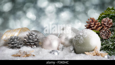 Arrangement de Noël élégant avec des boules d'argent, de rubans et de courbes avec des pommes de pin, avec bokeh scintillant retour Banque D'Images