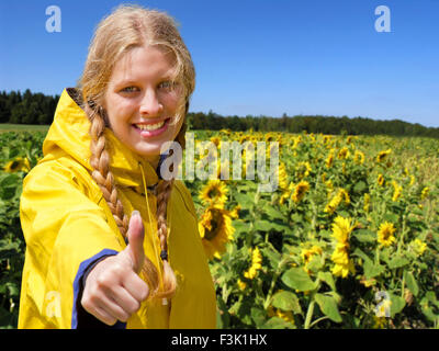 Jeune femme dans un champ de tournesol avec thumb up Banque D'Images