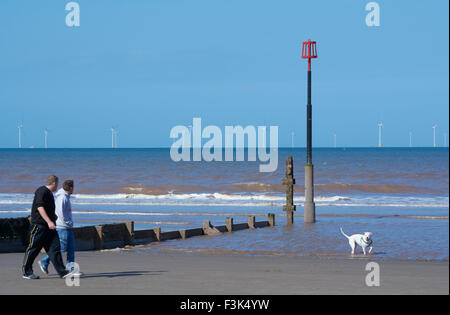 Les promeneurs sur la plage à Withersea donnant sur le parc éolien offshore de Westermost Rough - Yorkshire, Angleterre, Royaume-Uni Banque D'Images