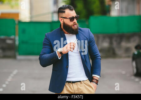 Homme avec une barbe fume cigarette électronique Banque D'Images