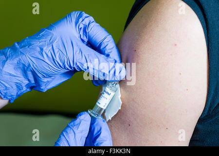 L'injection d'un médicament liquide dans un bras de patients se fait par deux mains porter des gants bleu Banque D'Images