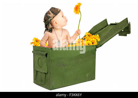 Cute baby girl dans une vieille boîte de munitions militaires avec des fleurs Banque D'Images