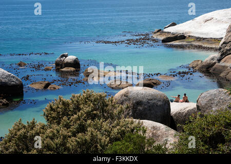 Couple assis sur le rocher surplombant l'océan, la plage de Boulders National Park, Simonstown, Afrique du Sud Banque D'Images