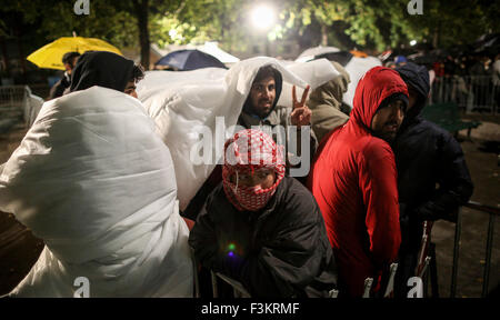 Berlin, Allemagne. 09Th Oct, 2015. Les réfugiés tentent de se protéger de la pluie pendant qu'ils attendent pour l'enregistrement et l'attribution d'un lieu de couchage dans les locaux de l'Office d'état de la Santé et du Bien-être social (LaGeSo) à Berlin, Allemagne, 09 octobre 2015. Photo : Kay Nietfeld/dpa/Alamy Live News Banque D'Images