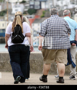 Un couple obèses marcher à côté du port de Brixham, Devon, England, UK Banque D'Images