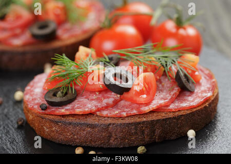 Sandwich au salami de seigle et les tomates de table en bois Banque D'Images