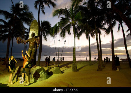 Les touristes la nuit en face de la Statue de Duke Kahanamoku, le père de surf qui a popularisé le sport réel. La plage de Waikiki. O'ah Banque D'Images