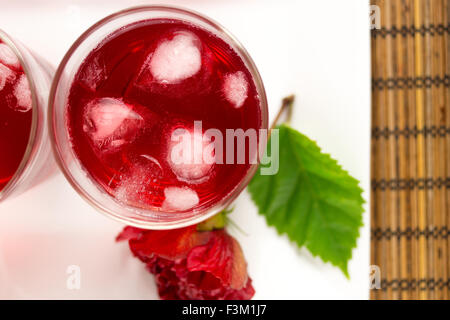 Rose et fleur d'hibiscus et fruits thé servi avec des cubes de glace Banque D'Images