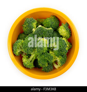 Pièces brutes de bouquets de brocoli dans un bol isolé sur un fond blanc. Banque D'Images