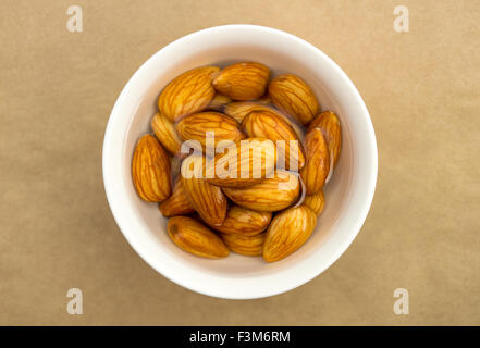 Amandes brutes à tremper dans un bol d'eau blanc Banque D'Images