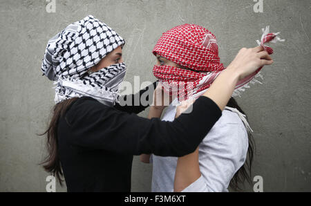 (151009) -- RAMALLAH, 9 octobre 2015 (Xinhua) -- une jeune fille palestinienne masqués contribue à un autre pour couvrir son visage, lors d'affrontements avec des soldats israéliens à Beit El, à la périphérie de la ville de Ramallah, en Cisjordanie, le 9 octobre 2015. Les médecins ont signalé que 6 manifestants blessés par balles réelles, d'autres avec 20 balles en caoutchouc. (Xinhua/Fadi Arouri) (l'azp) Banque D'Images