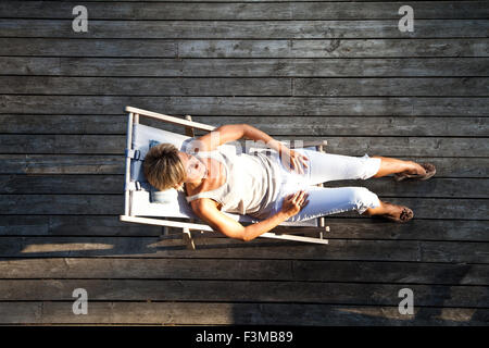 Cute woman détente sur un transat dans son jardin en plein air Banque D'Images