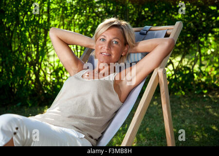 Cute woman détente sur un transat dans son jardin en plein air Banque D'Images