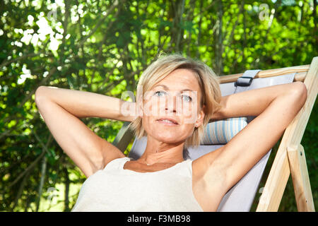 Cute woman détente sur un transat dans son jardin en plein air Banque D'Images