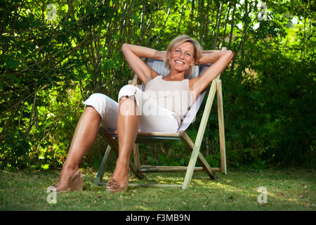 Cute woman détente sur un transat dans son jardin en plein air Banque D'Images