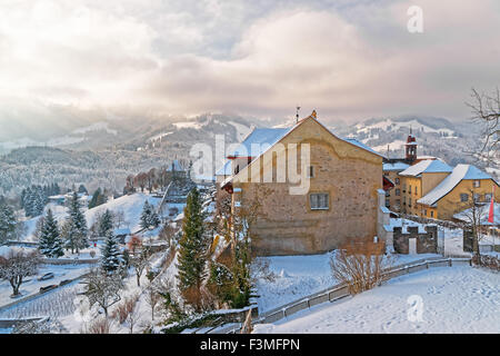 En hiver, la Suisse Gruyeres. Paysage de montagne couverte de neige de vieilles maisons en pierre en premier plan Banque D'Images