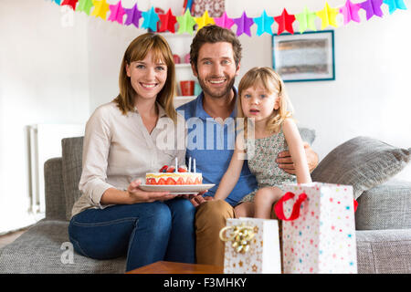 Petite fille fête d'anniversaire dans la maison blanche moderne avec les parents. Looking at camera Banque D'Images