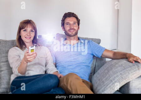 Couple de regarder un film avec un vidéo projecteur, sur un canapé confortable Banque D'Images