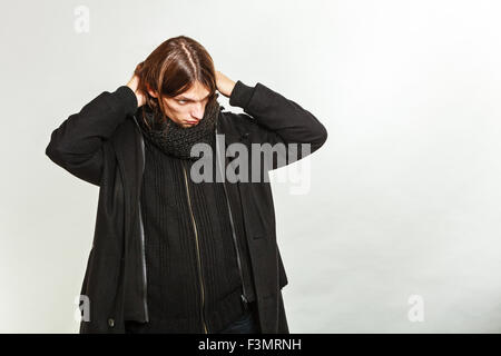 Portrait of handsome man à la mode manteau noir et écharpe. Jeune homme posing in studio. Mode d'hiver ou d'automne. Banque D'Images