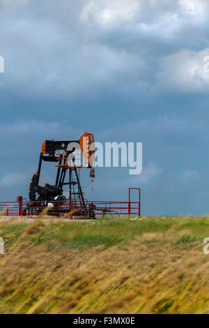 Une seule plate-forme pétrolière sur l'windly prairies, avec un ciel orageux. Banque D'Images