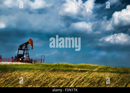 Une seule plate-forme pétrolière sur l'windly prairies, avec un ciel orageux. Banque D'Images