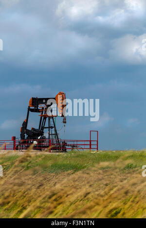 Une seule plate-forme pétrolière sur l'windly prairies, avec un ciel orageux. Banque D'Images