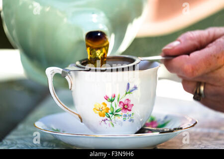 Verser le thé de près. Thé de l'après-midi. Femme versant une tasse de thé au salon de thé du village de Ludham. Norfolk broads Angleterre Royaume-Uni Banque D'Images