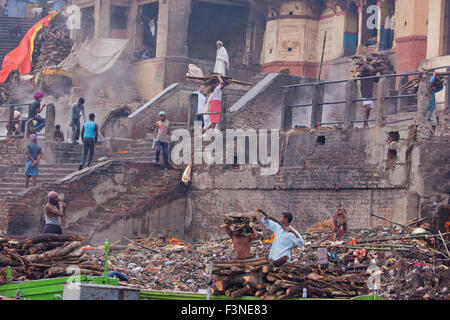 Transport des travailleurs du bois pour construire des grands bûchers à Manikarnika ghat sur le Gange à Varanasi tôt le matin Banque D'Images