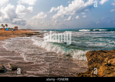 Le matin des petites vagues roulés sur une plage sauvage et dans lentement le ciel nuages flottants Banque D'Images