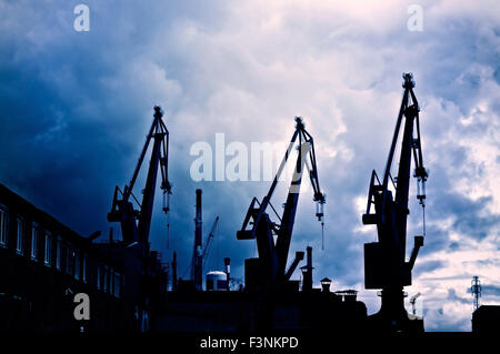 Image industrielle. Les nuages sombres et maussades sur chantier industriel avec les grues. Banque D'Images