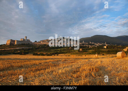 Village d'assise d'un champ de foin au coucher du soleil. Banque D'Images