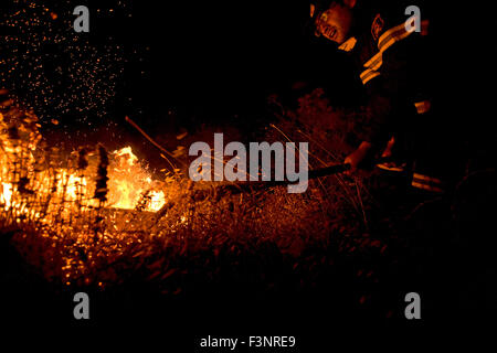 Un pompier qui est arrivée le Vorvonas la nuit, essaie de combattre l'incendie à l'aide d'un chat à l'origine des étincelles de feu pour voler dans l'air. Banque D'Images