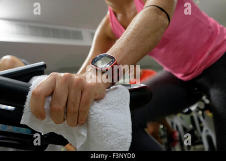 Gros plan d'une femme à l'aide d'un moniteur d'activité polaire portable pendant un spinning class Banque D'Images