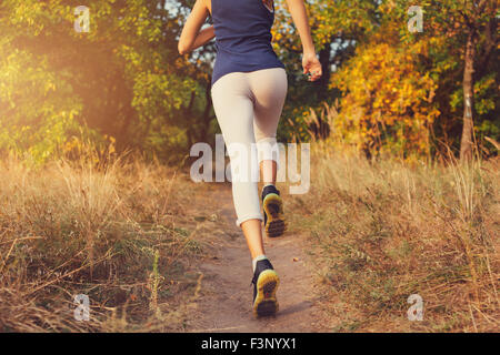 Jeune femme tournant sur un chemin rural au coucher du soleil dans la forêt d'automne. Fond sports Lifestyle