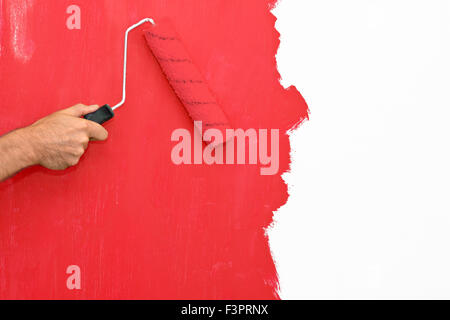 Peindre un mur à l'aide d'un rouleau avec de la peinture rouge Banque D'Images