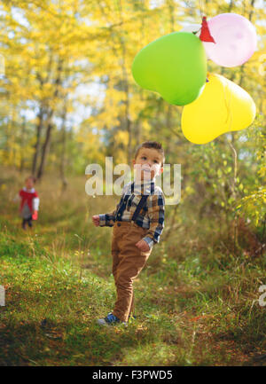 Garçon joyeux avec des ballons dans l'autumn Park Banque D'Images